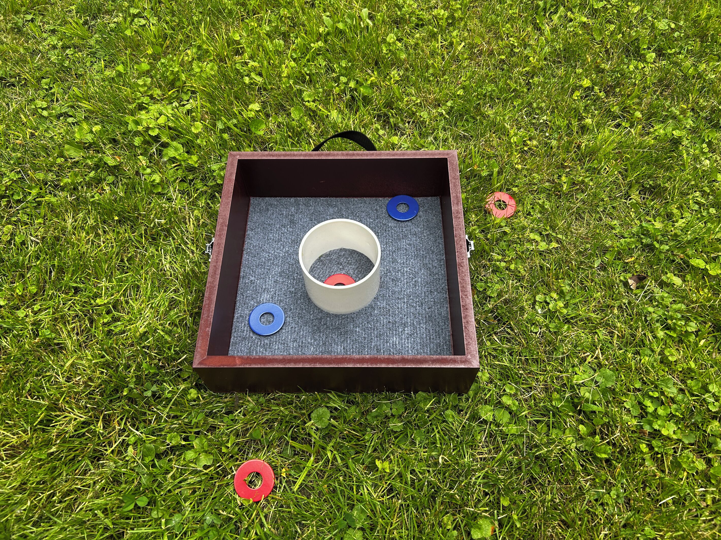 A square wooden box with a circular opening on top, placed on grass.