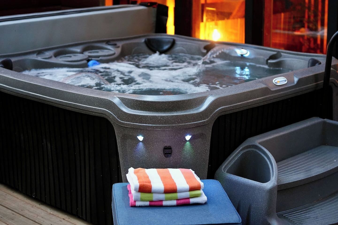 A hot tub with a control panel and a towel rack with colorful towels.