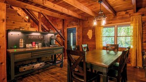 A rustic wooden interior with a coffee bar, dining table, and chairs.