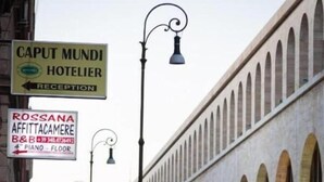A street with a hotel named "Caput Mundi Hotelier" and a piano store "Rossana Affittacamere B&B." - Little Appartment (Rome)