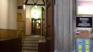 A hotel entrance with a reception desk, a staircase leading to the upper floor, and a signboard with contact information. - Little Appartment (Rome)