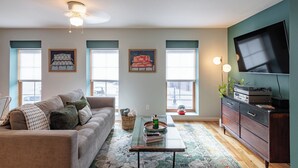 A living room with a sofa, coffee table, and a television on a stand.