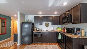 A modern kitchen with dark wood cabinets, a black refrigerator, a microwave, and a dishwasher.