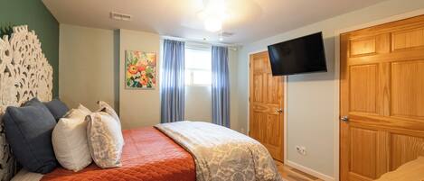 Un dormitorio con cama, televisión, armario de madera y ventana con cortinas.