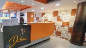Ein Empfangsbereich mit modernem Design, der ein auffälliges orangefarbenes Empfangspult und eine Wanduhr zeigt.