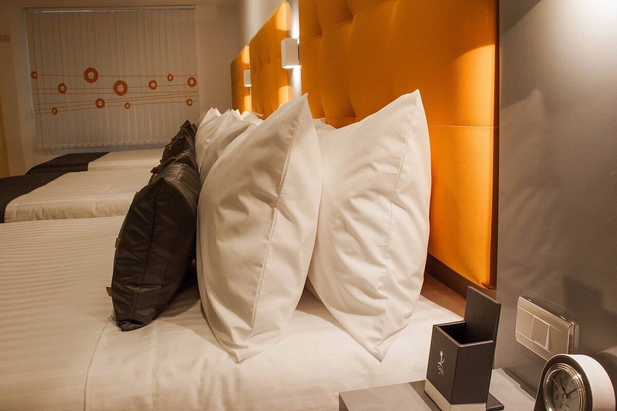 Et hotelværelse med to senge, en stor orange sengegavl og en væg med et cirkulært mønster.