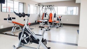 Ein Fitnessstudio mit Trainingsgeräten, darunter ein Crosstrainer und Kraftgeräte.