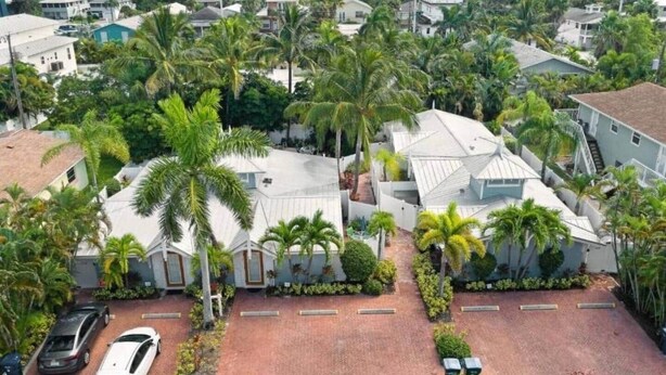 A residential area with houses surrounded by palm trees and a paved driveway. - Beachside 2BR AMI Villa with Pool Access (Holmes Beach)