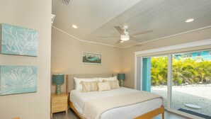 A bedroom with a bed, nightstands, and artwork on the walls.