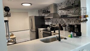 Een moderne keuken met een groot eiland, roestvrijstalen apparatuur en een decoratieve spatwand.