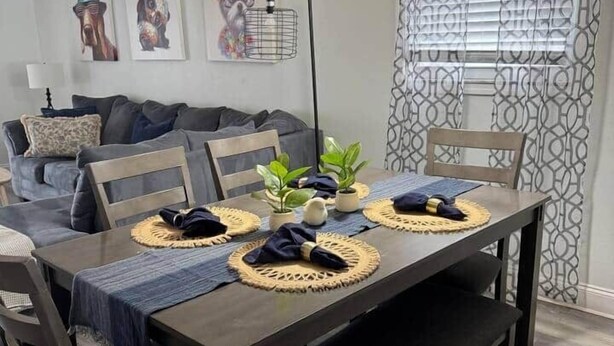 A dining area with a dark wooden table, four chairs, and a hanging lamp.