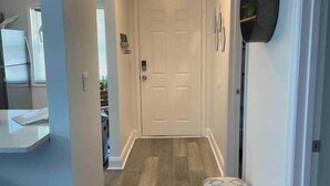 A hallway with a bench, a door, and a wall-mounted bag rack.