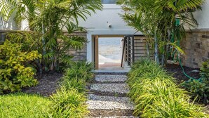 A pathway leading to a building entrance surrounded by lush greenery and a stone wall. - Waterfront 2BR on Manatee River Near Anna Maria Island (West Bradenton)