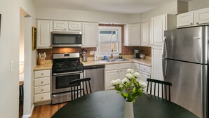 Une cuisine moderne avec des meubles blancs, des appareils en acier inoxydable et une table à manger avec des chaises.