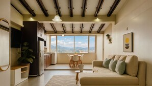 A modern living room with a sofa, a dining area, and a kitchen.