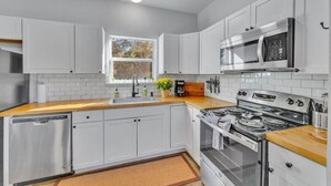 A modern kitchen with white cabinets, a stainless steel dishwasher, a built-in oven, and a microwave.