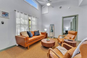 A living room with a sofa, armchairs, a coffee table, and a large mirror.