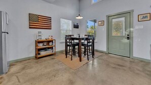 A dining area with a table and chairs, a flag on the wall, and a door with a window.