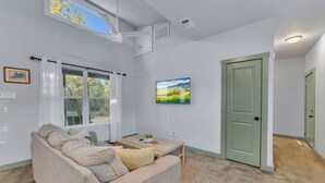 A living room with a sofa, a coffee table, a painting, and a door.