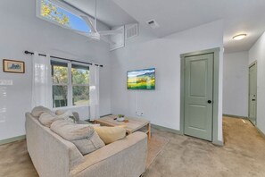Un salon avec un canapé, une table basse, un tableau et une porte.