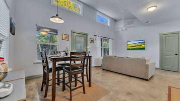A dining area with a table and chairs, a sofa, and a television.