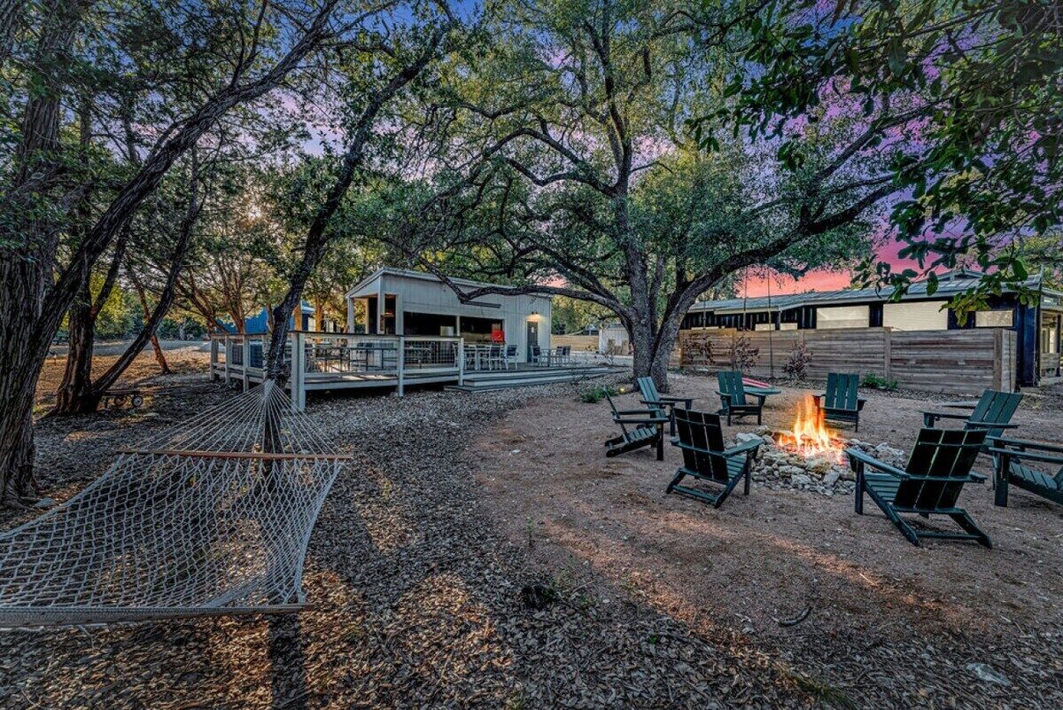 A rustic outdoor area with a hammock, fire pit, and seating.