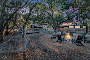 Un espacio al aire libre rústico con una hamaca, una fogata y asientos.