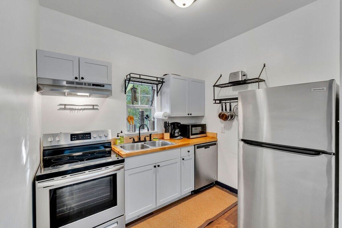 A compact kitchen with white cabinets, a stainless steel refrigerator, a built-in oven, and a microwave.