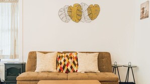 Un salon comprenant un canapé, un coussin décoratif à motifs, une table basse et une œuvre d’art murale.