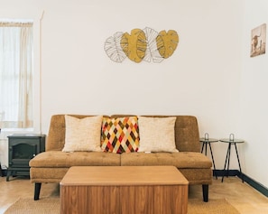 Un salon comprenant un canapé, un coussin décoratif à motifs, une table basse et une œuvre d’art murale.