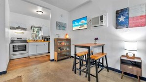 Une cuisine compacte dotée d’appareils électroménagers modernes, un coin repas avec des tabourets et une petite table.