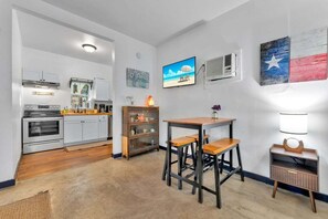 Une cuisine compacte dotée d’appareils électroménagers modernes, un coin repas avec des tabourets et une petite table.