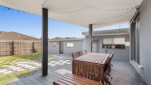 An outdoor patio with a wooden table and chairs, string lights, and a covered area. - Gorgeous 3-bed House With Spacious Shared Backyard (Melbourne)
