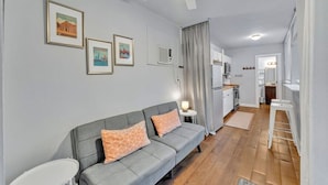 A modern living room with a grey sofa, a ceiling fan, and framed pictures on the wall.