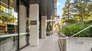 A modern building with a sign reading "Autograph Collection" and a staircase leading to an outdoor area with plants and seating. - Central 1-bed Apartment With Pool (Canberra)