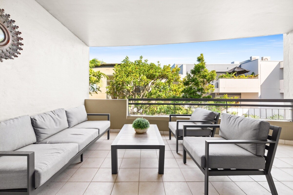 A balcony with a sofa, chairs, and a table.