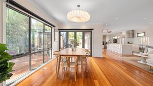 A modern kitchen with white cabinets, a stainless steel range hood, and a large island with bar stools.