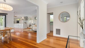 A spacious living area with hardwood flooring, a dining table, and a kitchen in the background.