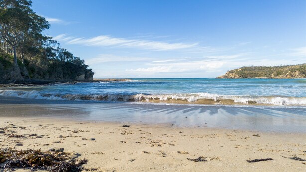 A beach with clear skies, calm waves, and a rocky coastline. - Secluded 3-bed Retreat Moments to the Beach (Surf Beach)