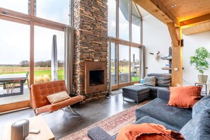 Una sala de estar moderna con chimenea de piedra, ventanas amplias y vistas al exterior.