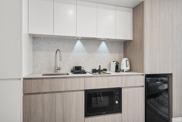 A modern kitchen with a built-in microwave, a coffee maker, and a toaster on the countertop. - Chic Studio Stay Near Cafes and Coastline (Perth)