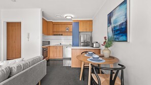 Une cuisine compacte avec des meubles en bois, un four encastré et un coin repas comprenant une table et des chaises.