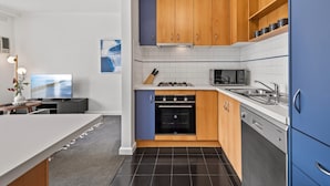 Une cuisine moderne avec des meubles en bois, un four à micro-ondes, un four traditionnel et un lave-vaisselle.