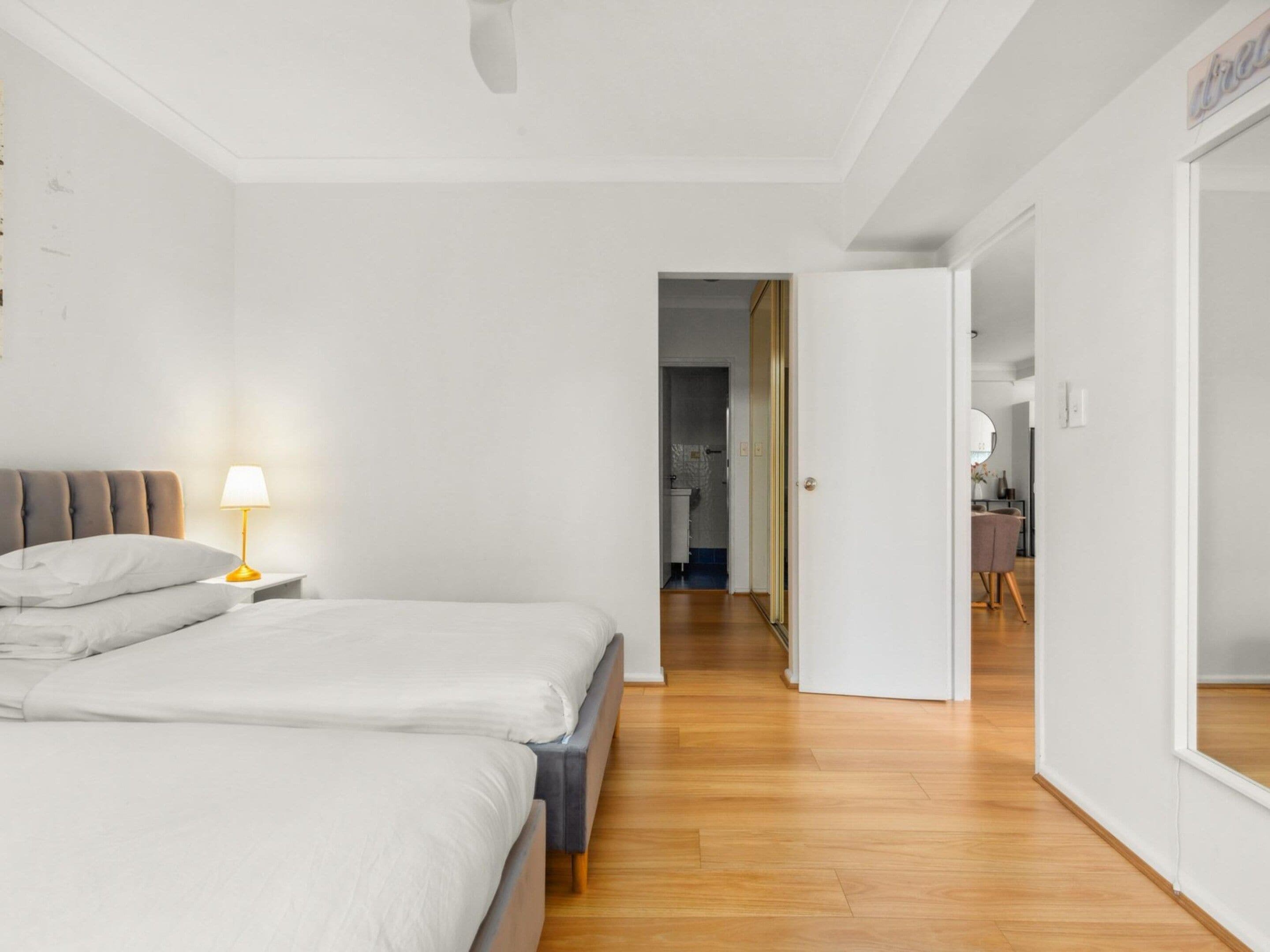 A hotel room with a bed, bedside lamp, and a view into the bathroom.