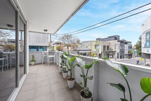 A balcony with potted plants, a seating area, and a view of the street. - Sleek South Yarra 2-bed With Alfresco Dining (Melbourne)