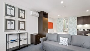 A modern living room with a grey sofa, a black console table with a blue bowl, and a dark wooden wardrobe. - Cosy Studio in the City Centre (Melbourne)