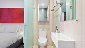 A modern hotel bathroom with a toilet, sink, and mirror. - Cosy Studio in the City Centre (Melbourne)