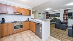 Une cuisine de taille réduite, dotée de meubles en bois, d’une cuisinière en acier inoxydable et d’un lave-vaisselle.