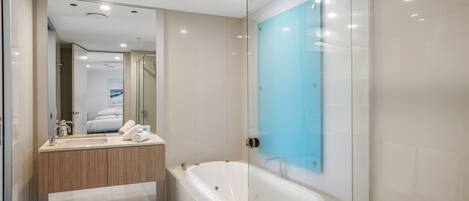 Un baño moderno con ducha de mampara de vidrio, una bañera independiente y un tocador con espejo.