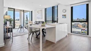 A modern kitchen with a central island, large windows, and a view of the city. - Stylish 2-bed Apartment With Rooftop BBQ Access (Perth)